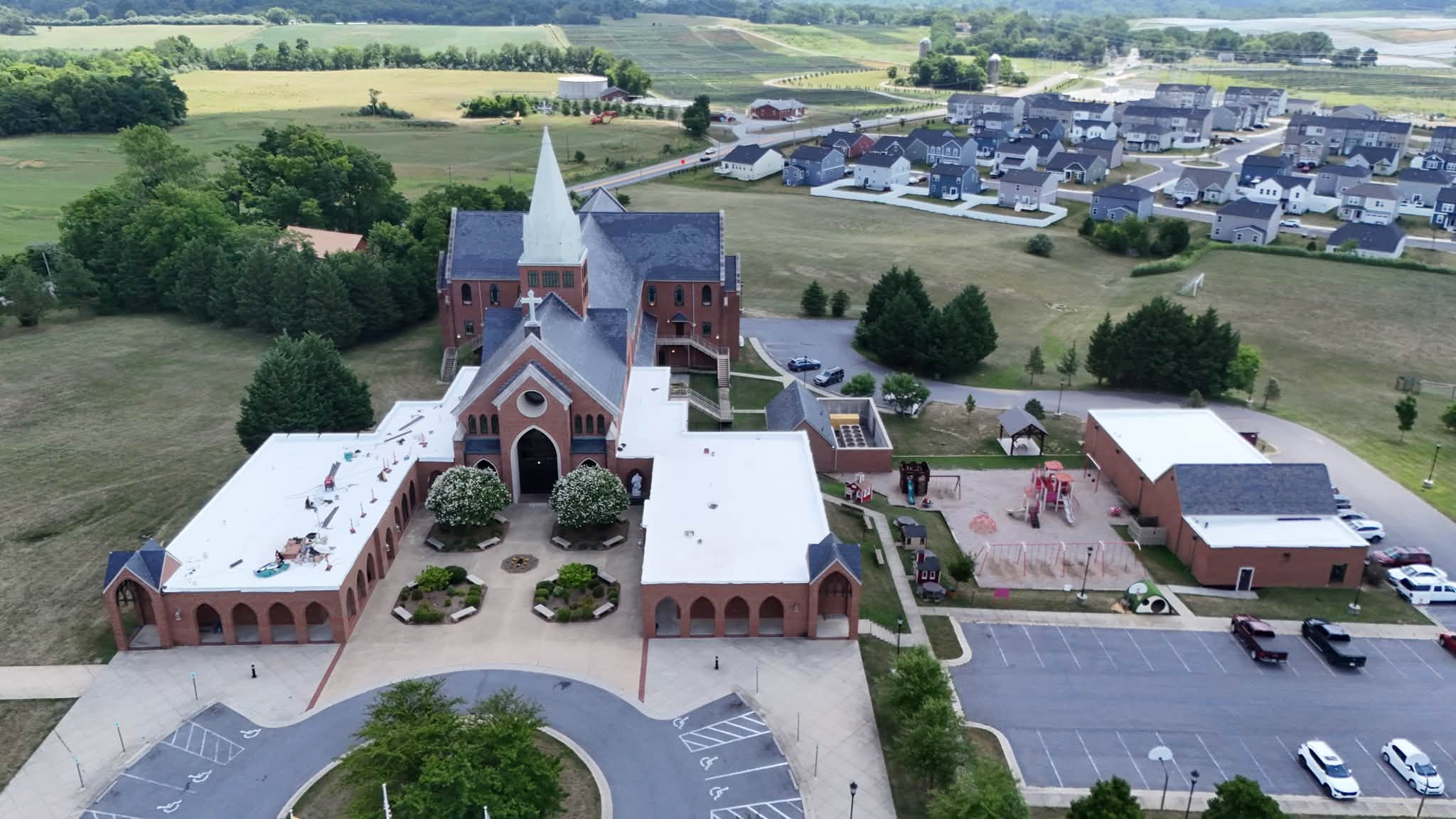 Aerial of a brick church and school where Black Stone Roofing installed white membrane flat roofs