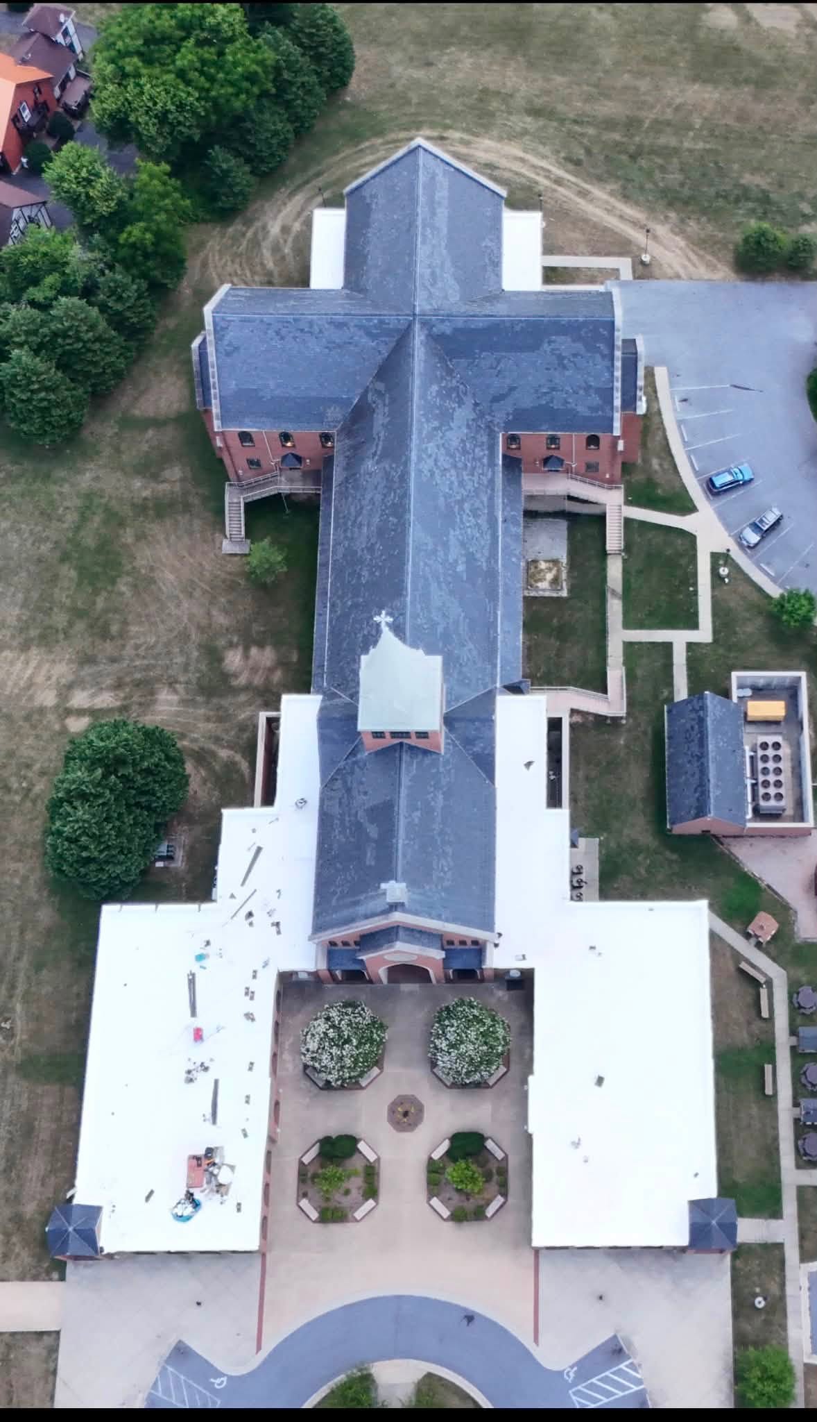 Top-down aerial of a church campus with new white membrane flat roofs installed by Black Stone Roofing