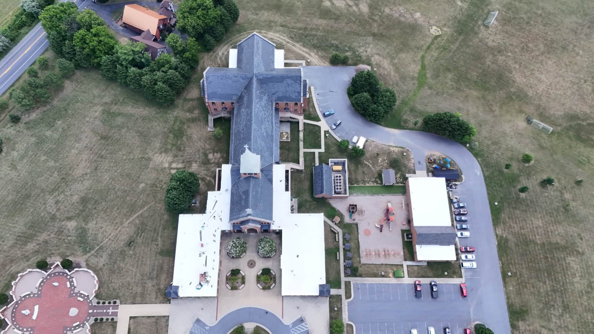 Drone view of completed white membrane and shingle roofing by Black Stone Roofing on a church and school campus