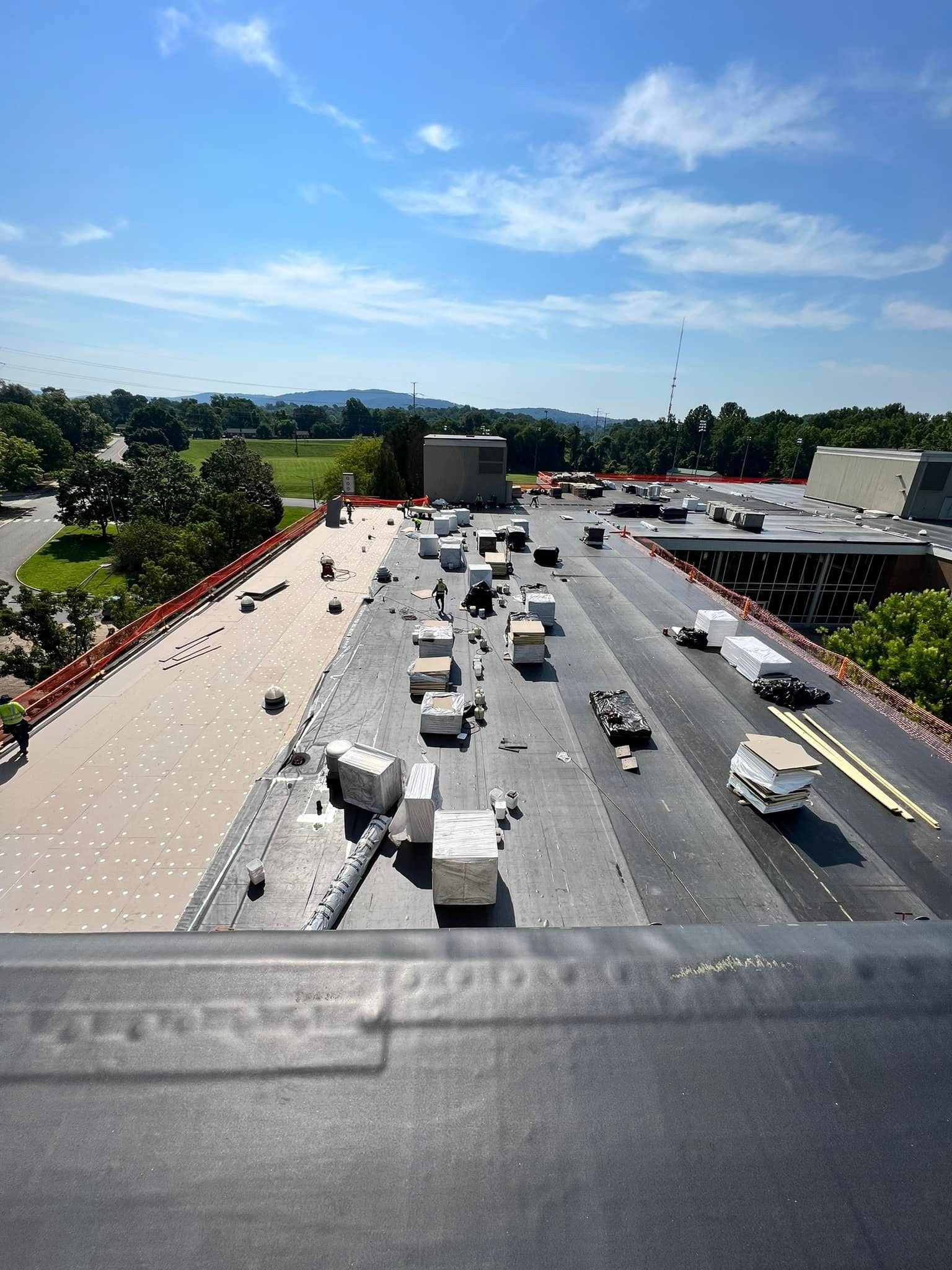 Roofing crew installing rigid insulation board and single ply membrane on a commercial flat roof in Martinsburg WV