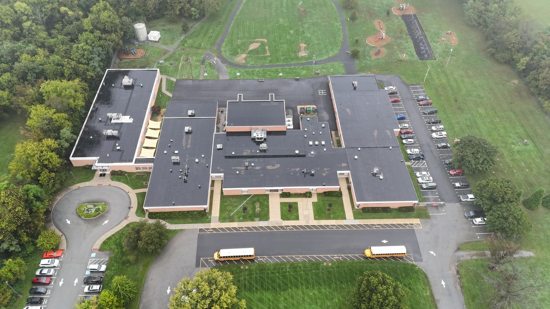 Aerial view of a school building with a large black flat membrane roof and rooftop HVAC units, commercial single ply roofing by Black Stone Roofing in Martinsburg WV