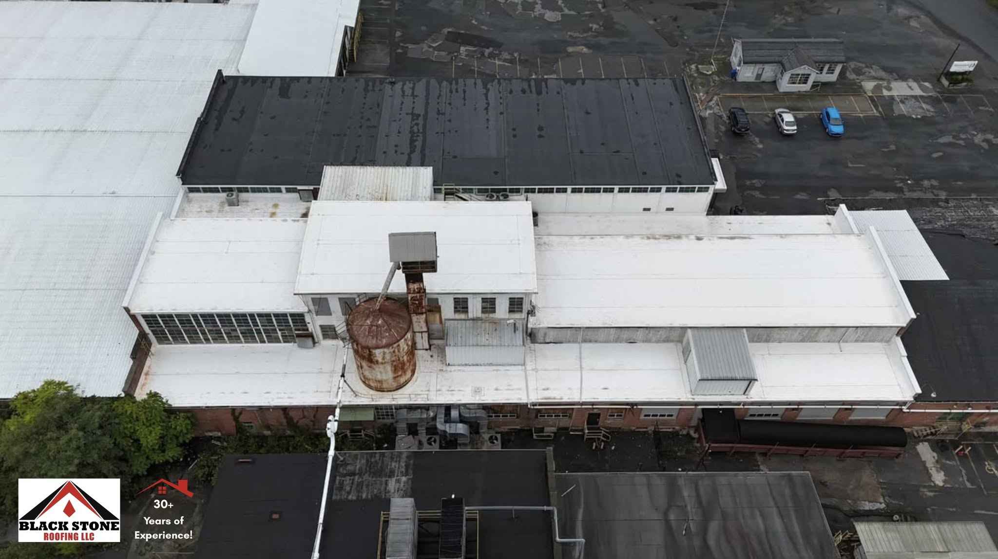 Aerial view of new white membrane roofing by Black Stone Roofing on an industrial plant