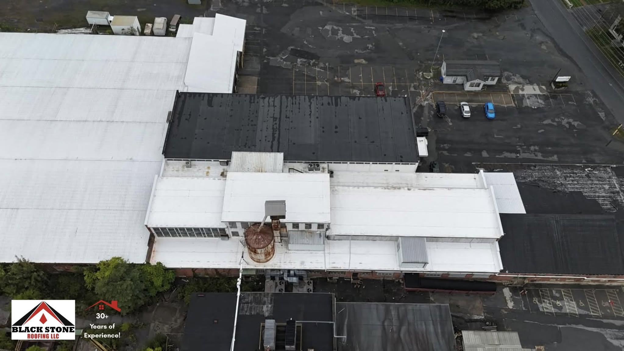 Top-down drone view of an industrial facility with white membrane roofing by Black Stone Roofing