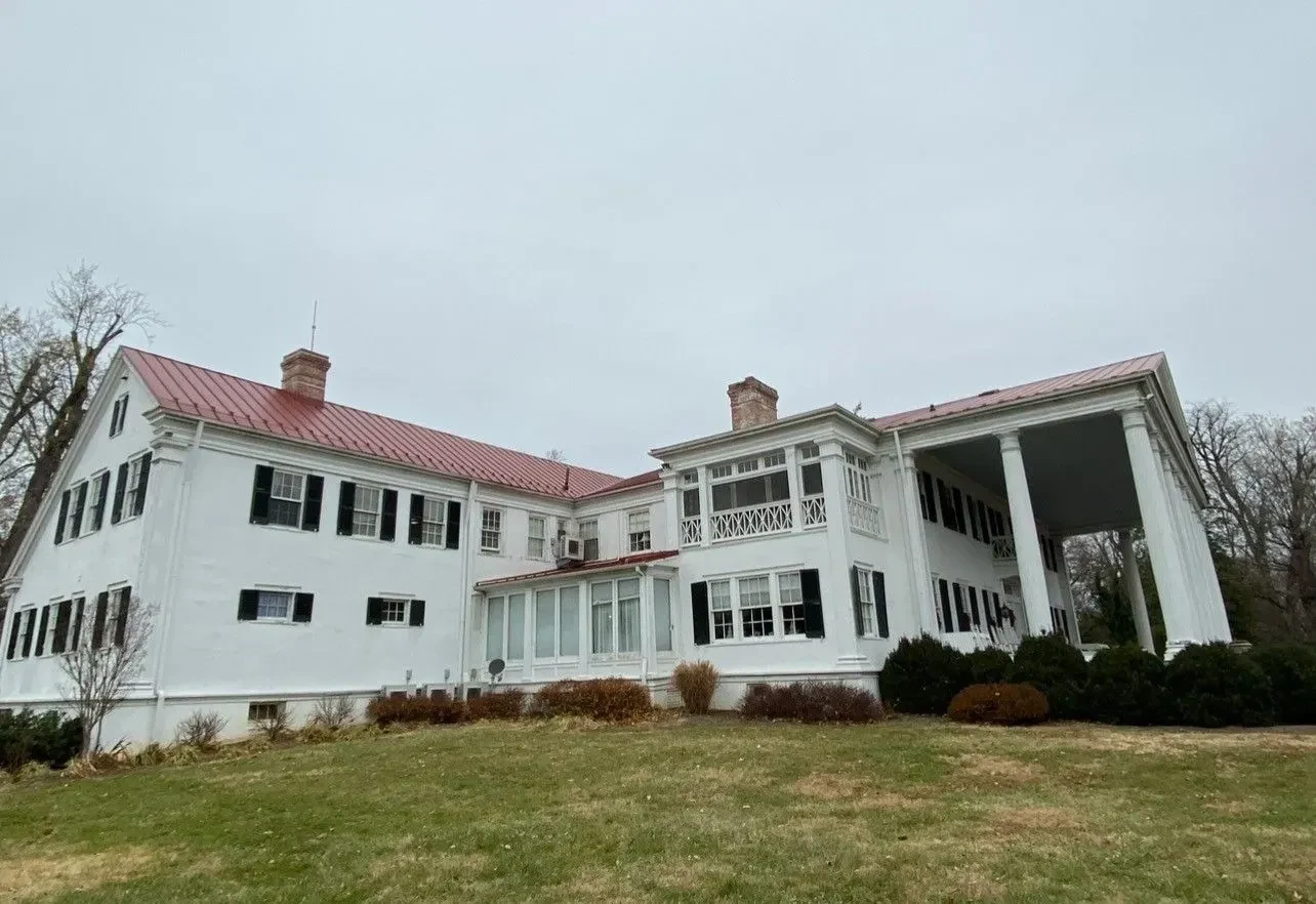 Historic home in Martinsburg WV with a new red standing seam metal roof over steep gables and dormers, historic district roofing by Black Stone Roofing, serving Winchester VA, Charles Town WV, and Hagerstown MD