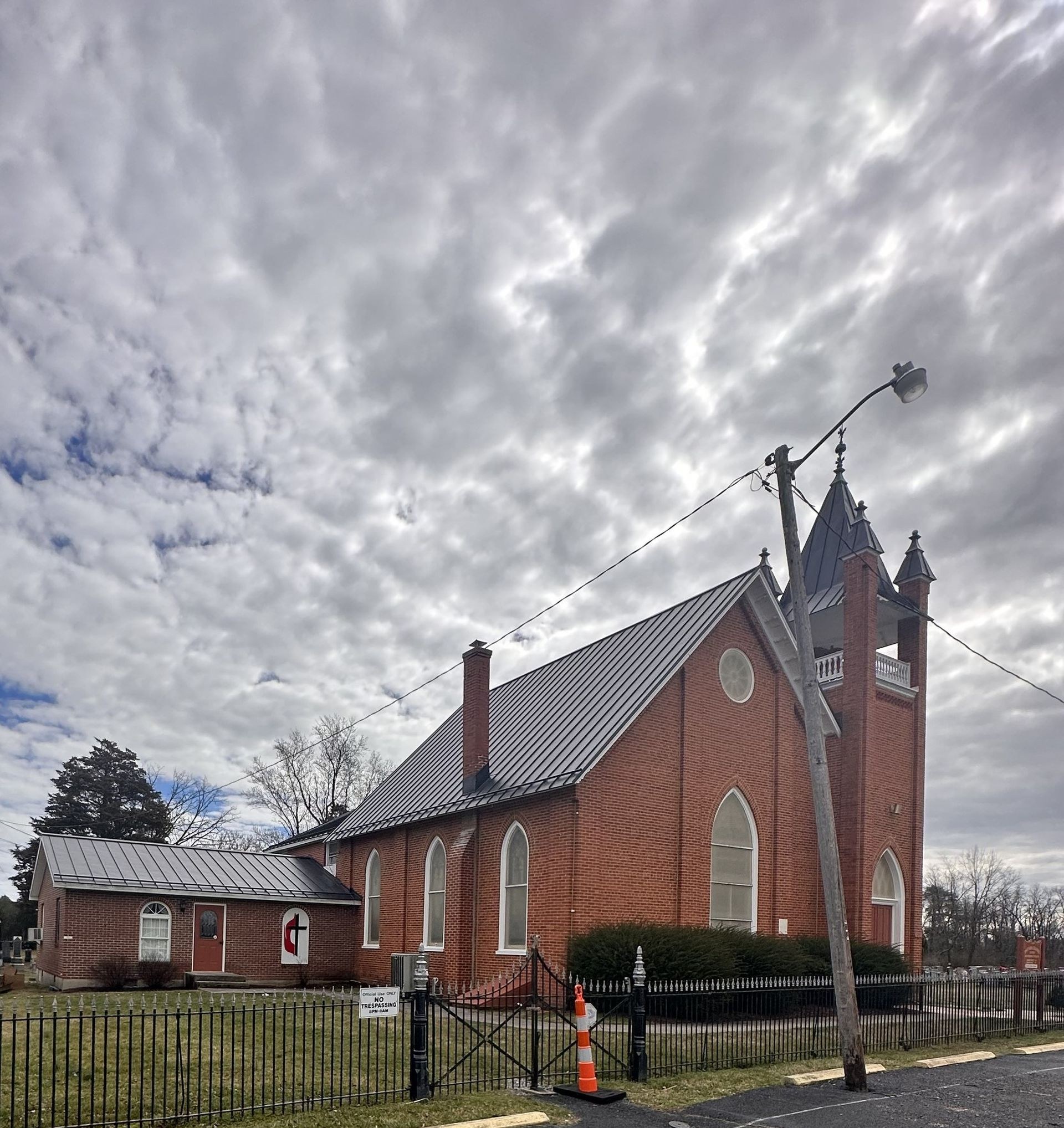 Dark charcoal standing seam metal roof on a red brick church with a bell tower and steeple, installed by Black Stone Roofing serving Martinsburg WV