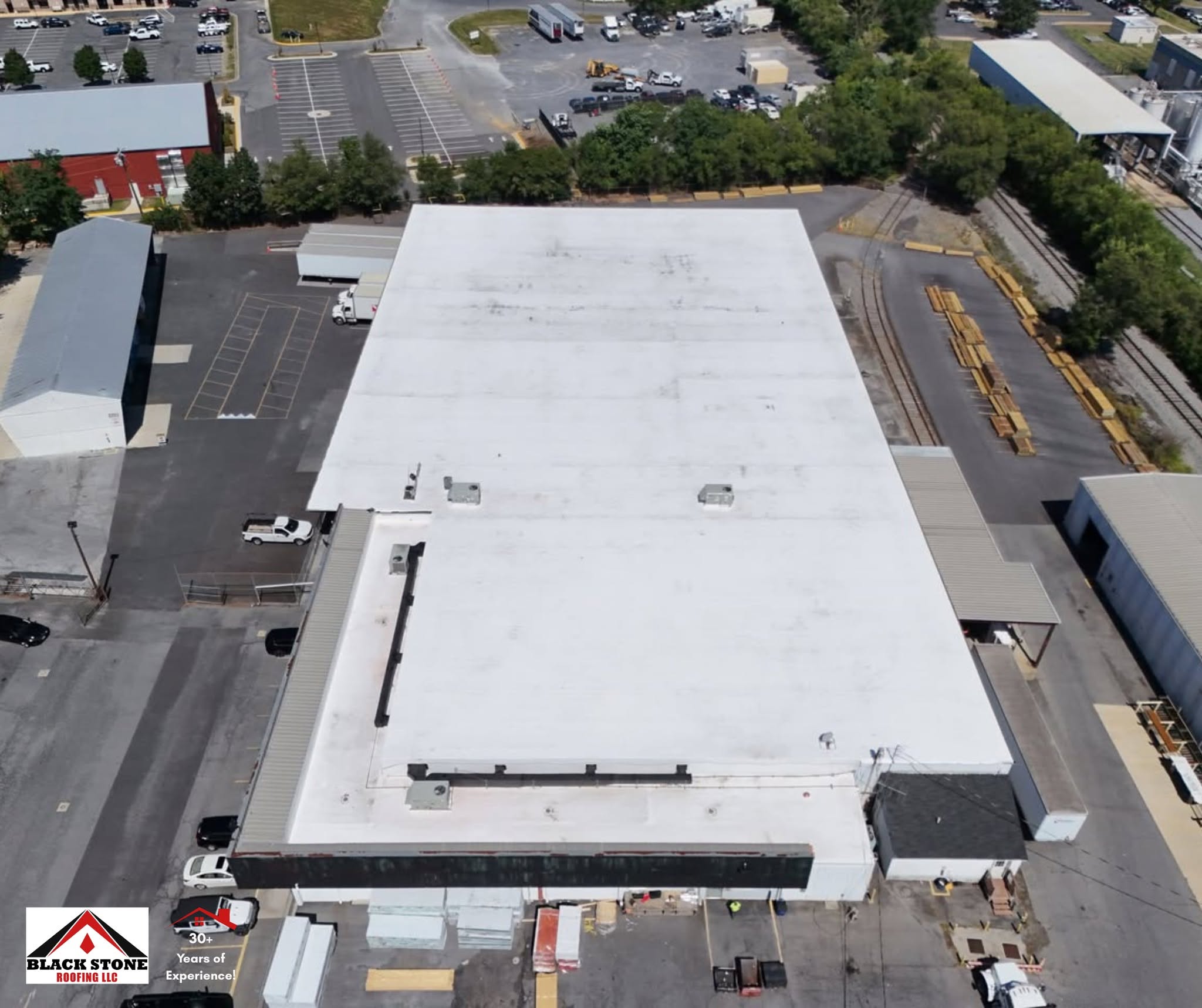 Top-down aerial of a full white membrane roof replacement by Black Stone Roofing on a warehouse